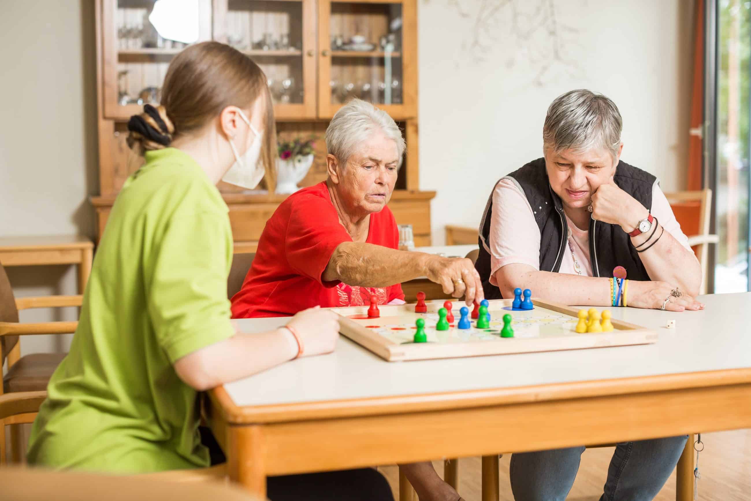 Zwei Frauen und Mitarbeiterin spielen Brettspiel