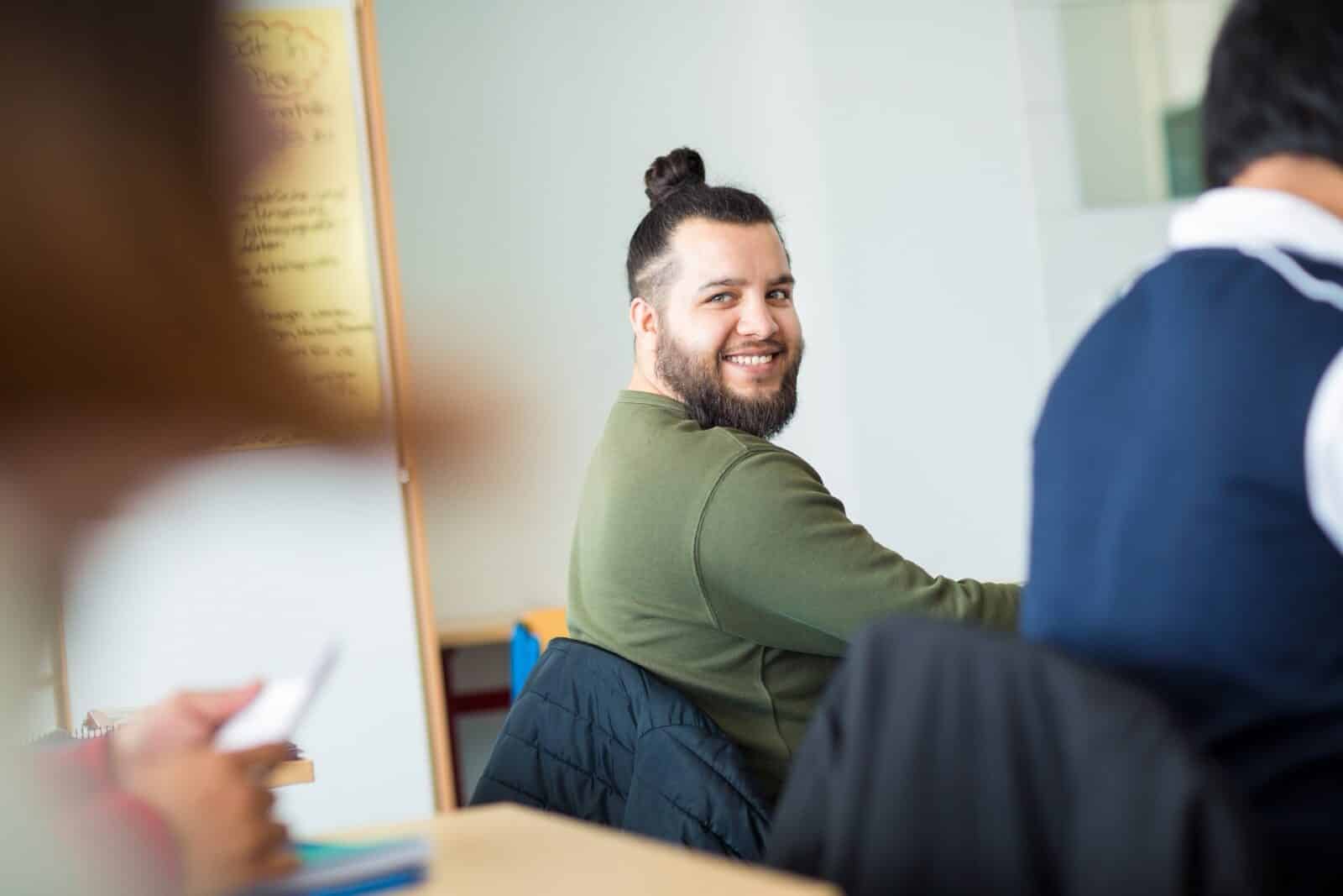 Ein lächelnder Teilnehmer dreht sich in einem Seminarraum um